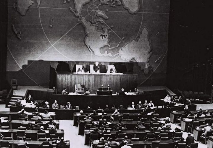 Schwarzweißfotografie der UN-Generalversammlung in New York aus dem Jahr 1947. Der Saal ist von oben aufgenommen. Die Sitzreihen der Vollversammlung sind von hinten zu sehen.